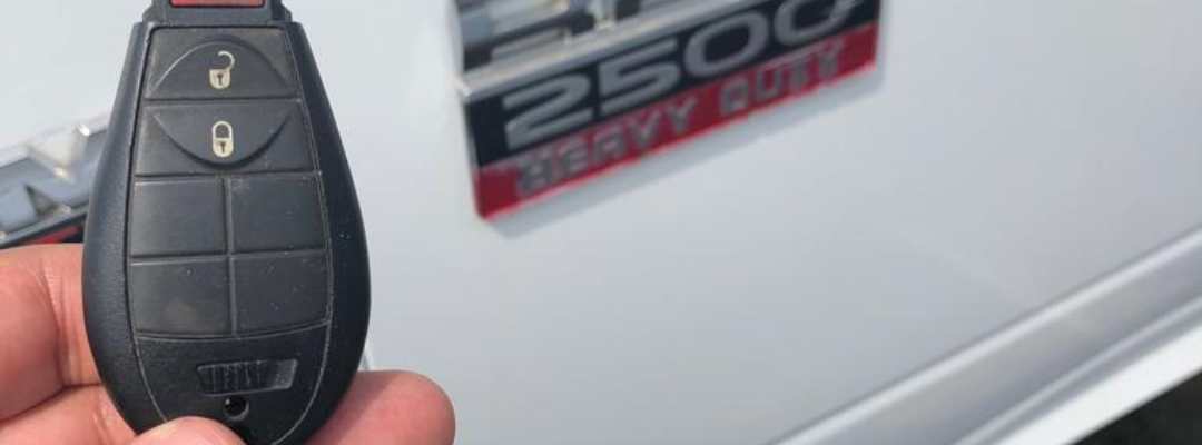 A Dodge key fob held next to a Ram 2500 badge