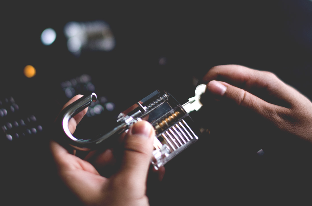 A locksmith holding a clear practice padlock showing the pins inside